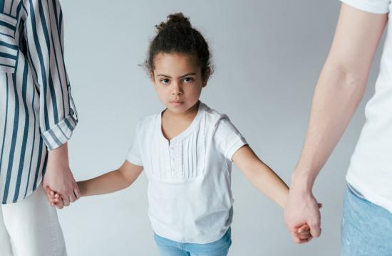 child holding hands between two parents