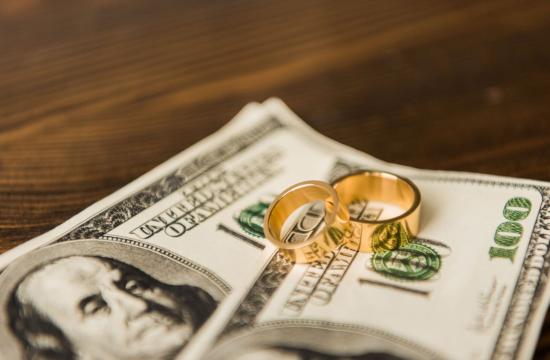 close up of cash and wedding rings on a wooden table